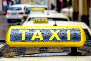 Close-up of a yellow taxi sign covered in raindrops.