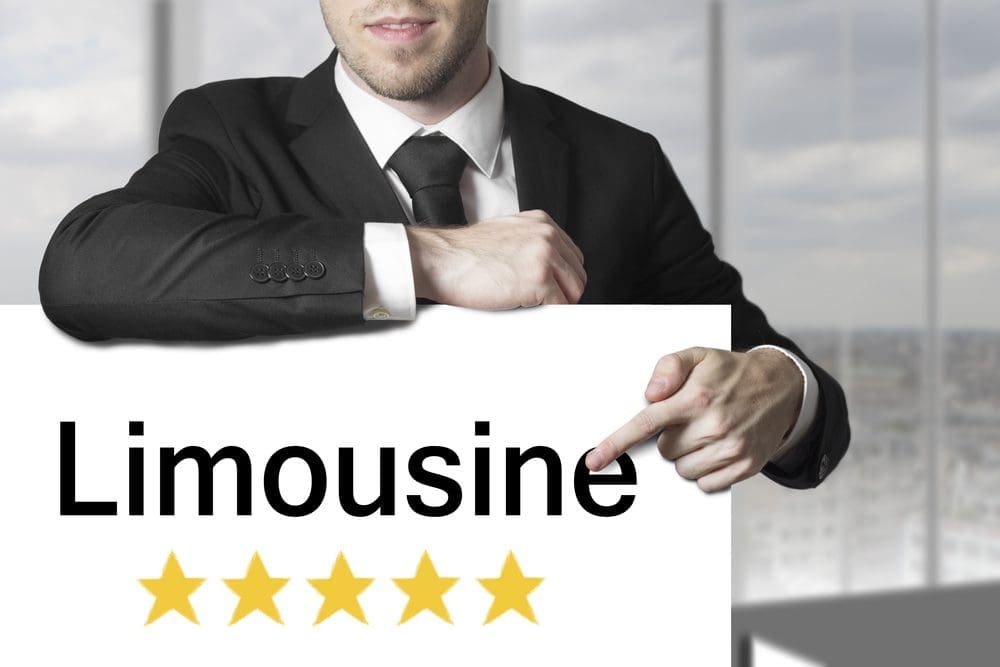 Man in suit holding a five-star limousine sign.