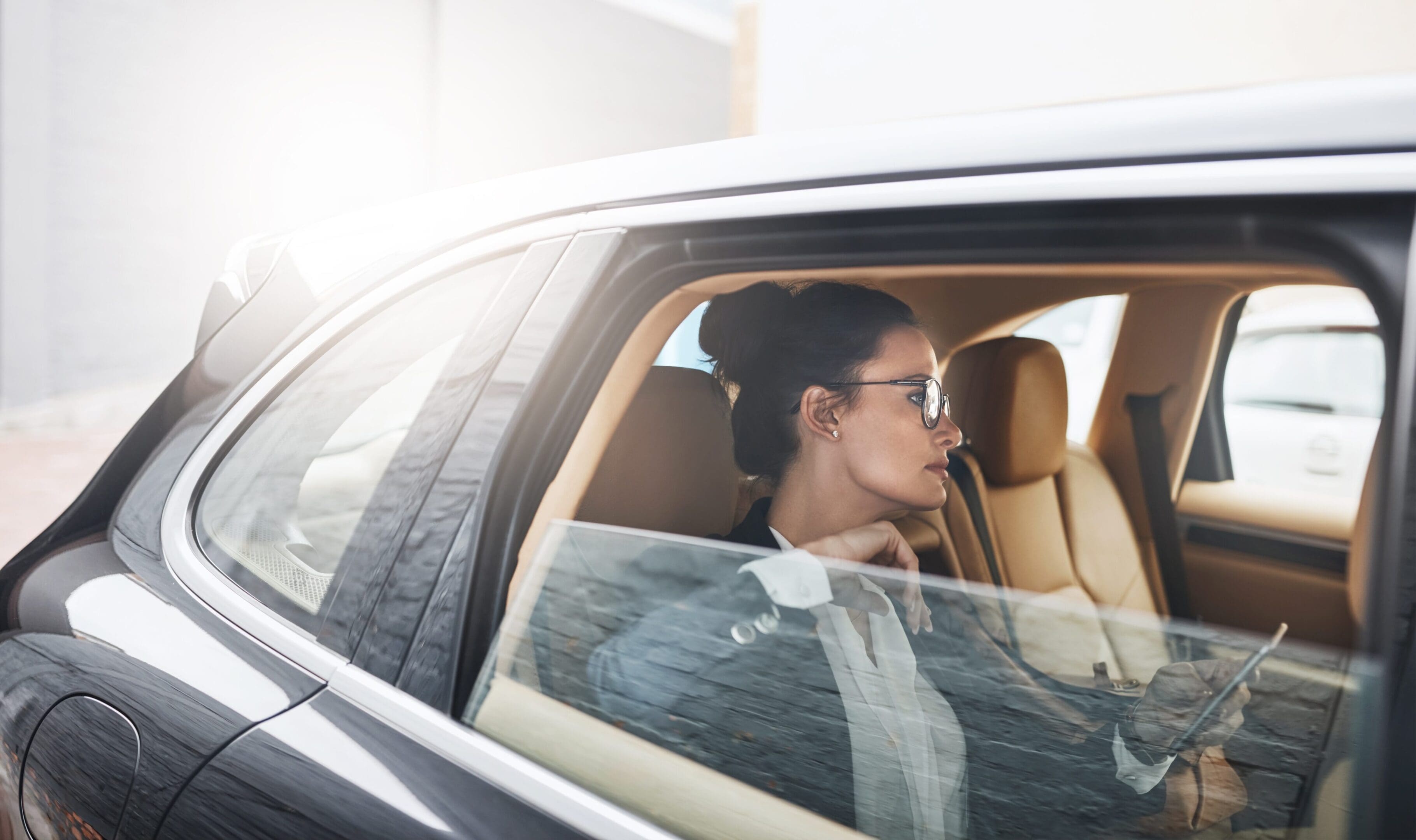Woman sitting in a car, looking out the window thoughtfully.