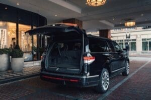 Black SUV with open trunk parked under a covered entrance at night.