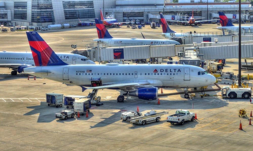 Delta Airlines planes parked at airport gates with ground crew preparing for flights.